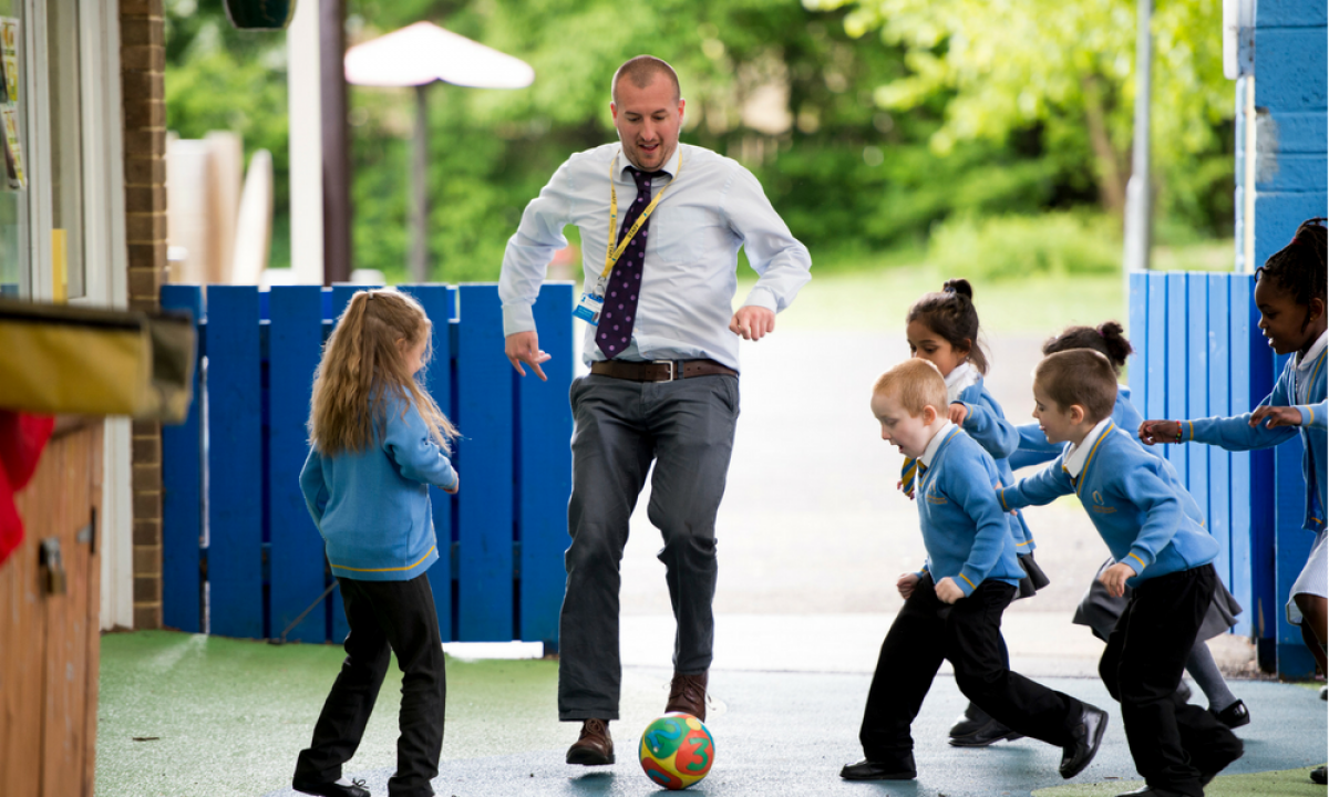Teacher playing football with children